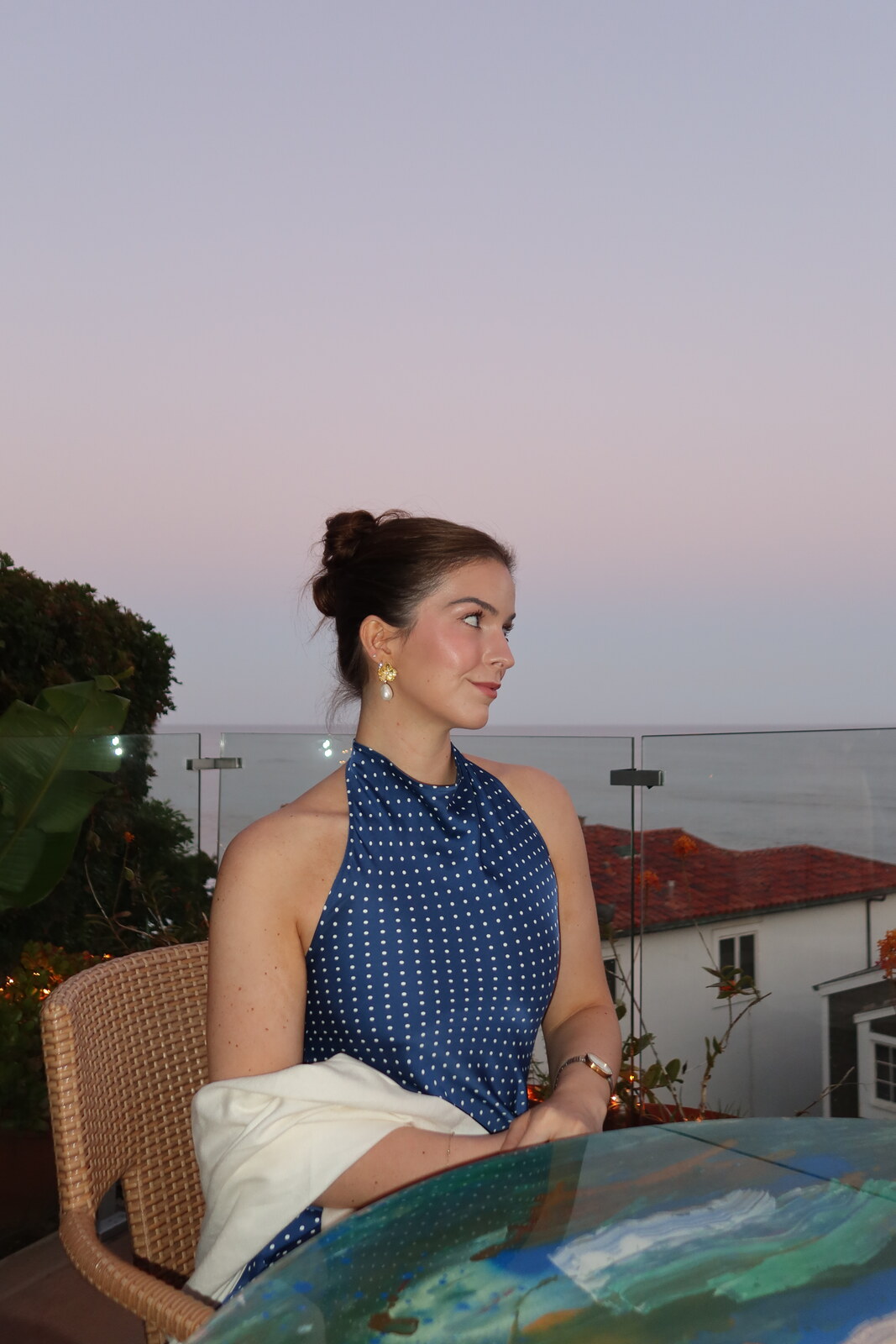 Emily at dusk on a terrace, wearing a blue polka-dot top